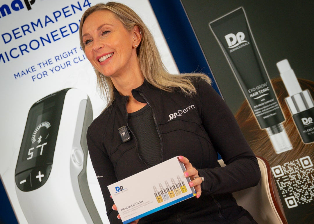Woman in a black Dr. Derm jacket holding a product box with promotional materials in the background.